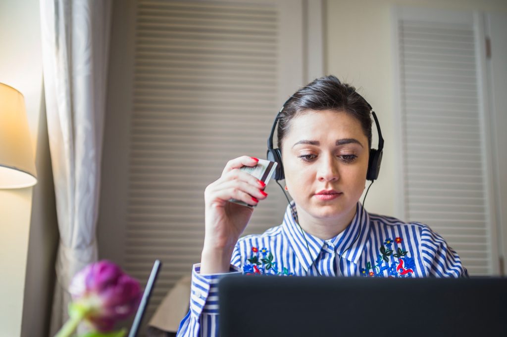 Urdu call center jobs in Islamabad with a female customer service representative wearing headphones and a striped shirt, working on a laptop.